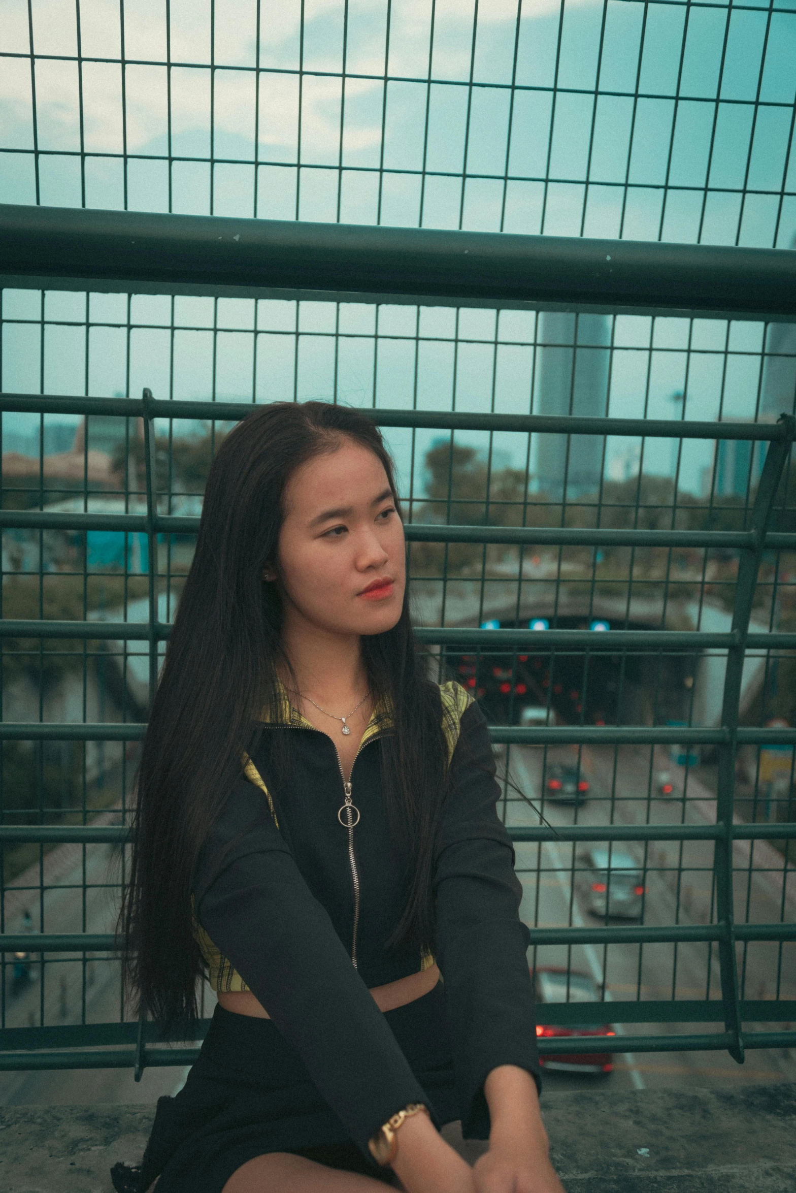 a young woman in short skirt sitting next to fence