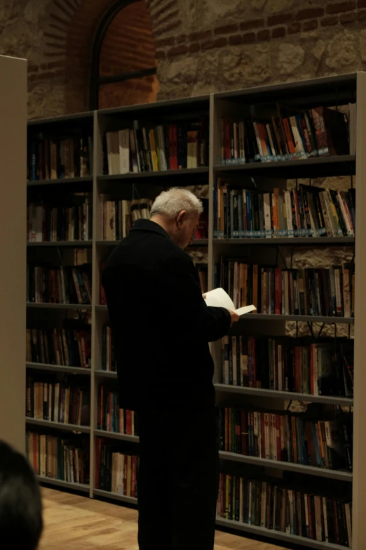 a man looking at a book in a liry