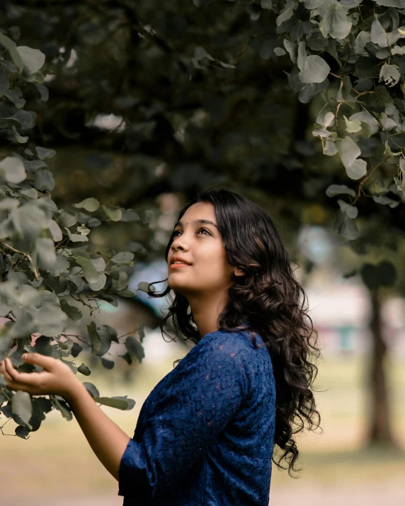 a woman standing under some green leaves