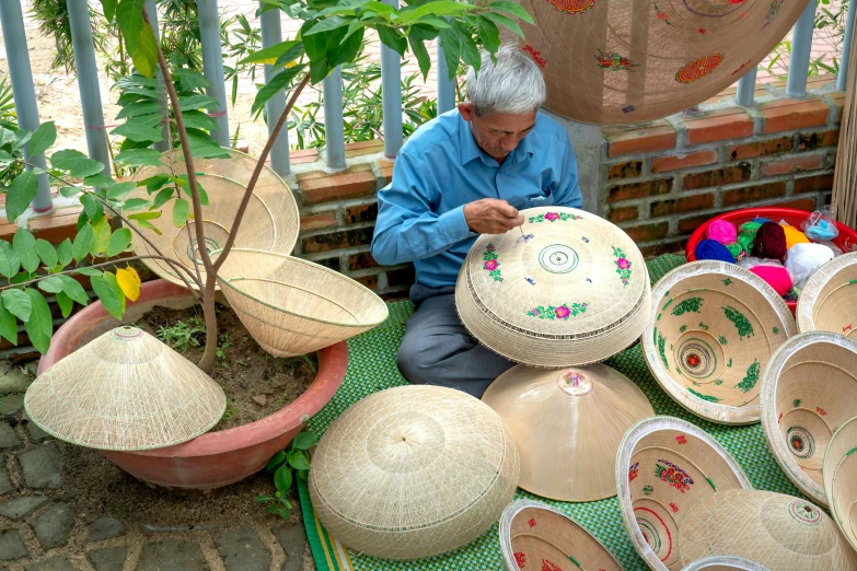 an old man with various baskets sitting on the ground