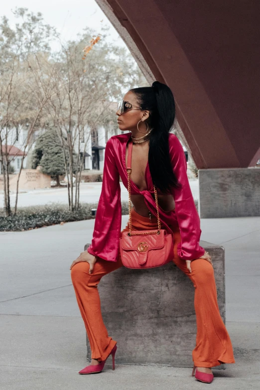 a woman is wearing a red outfit and holding a pink purse