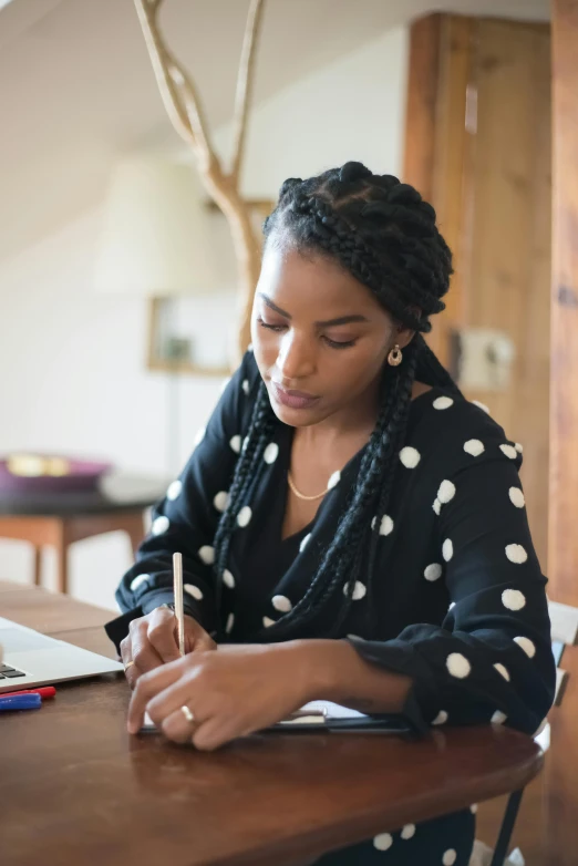 a woman sitting at a desk writing in her notebook