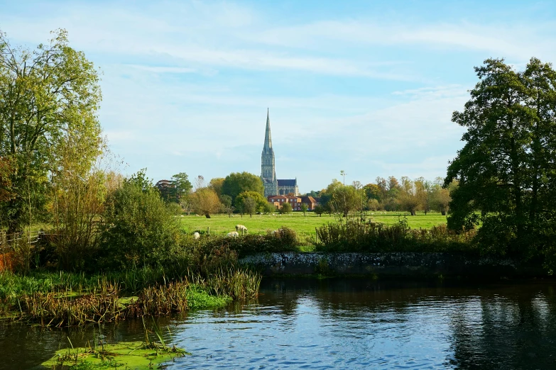 a small lake in a green field near a church