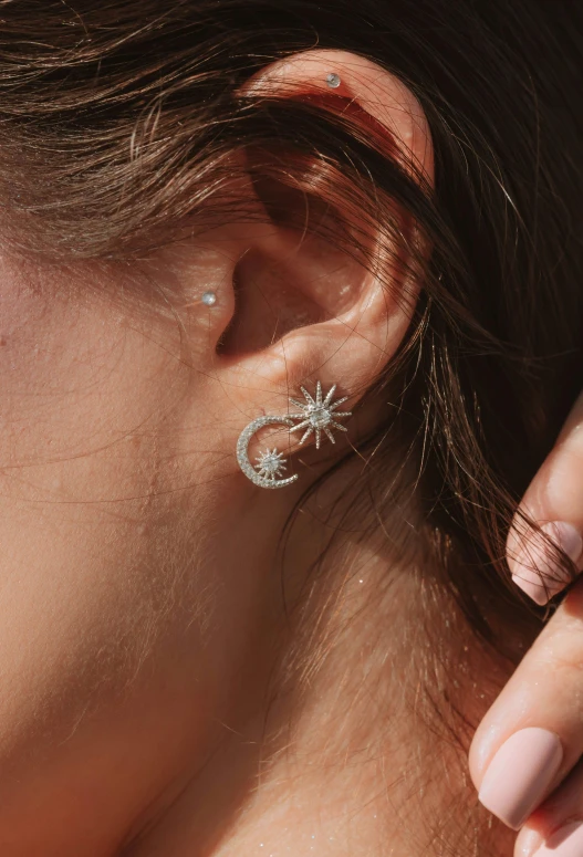 a woman wearing a pair of small ear piercings