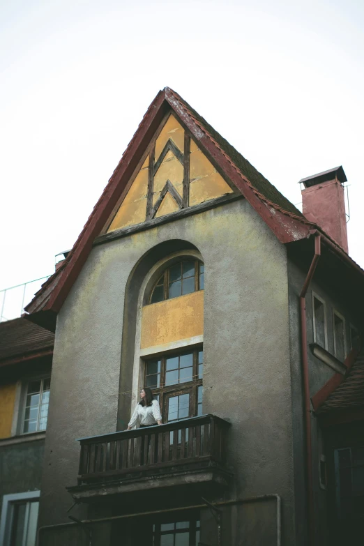 a person stands outside an open window on an older house