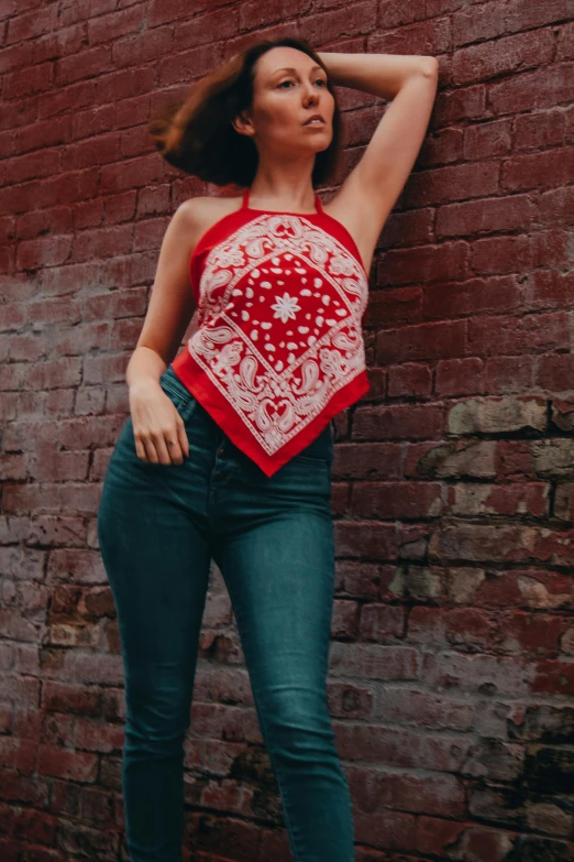 a beautiful woman leaning against a brick wall