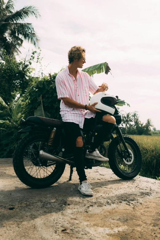 a man sitting on a motorcycle with palm trees