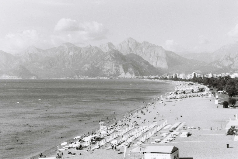 a black and white picture of a beach next to mountains