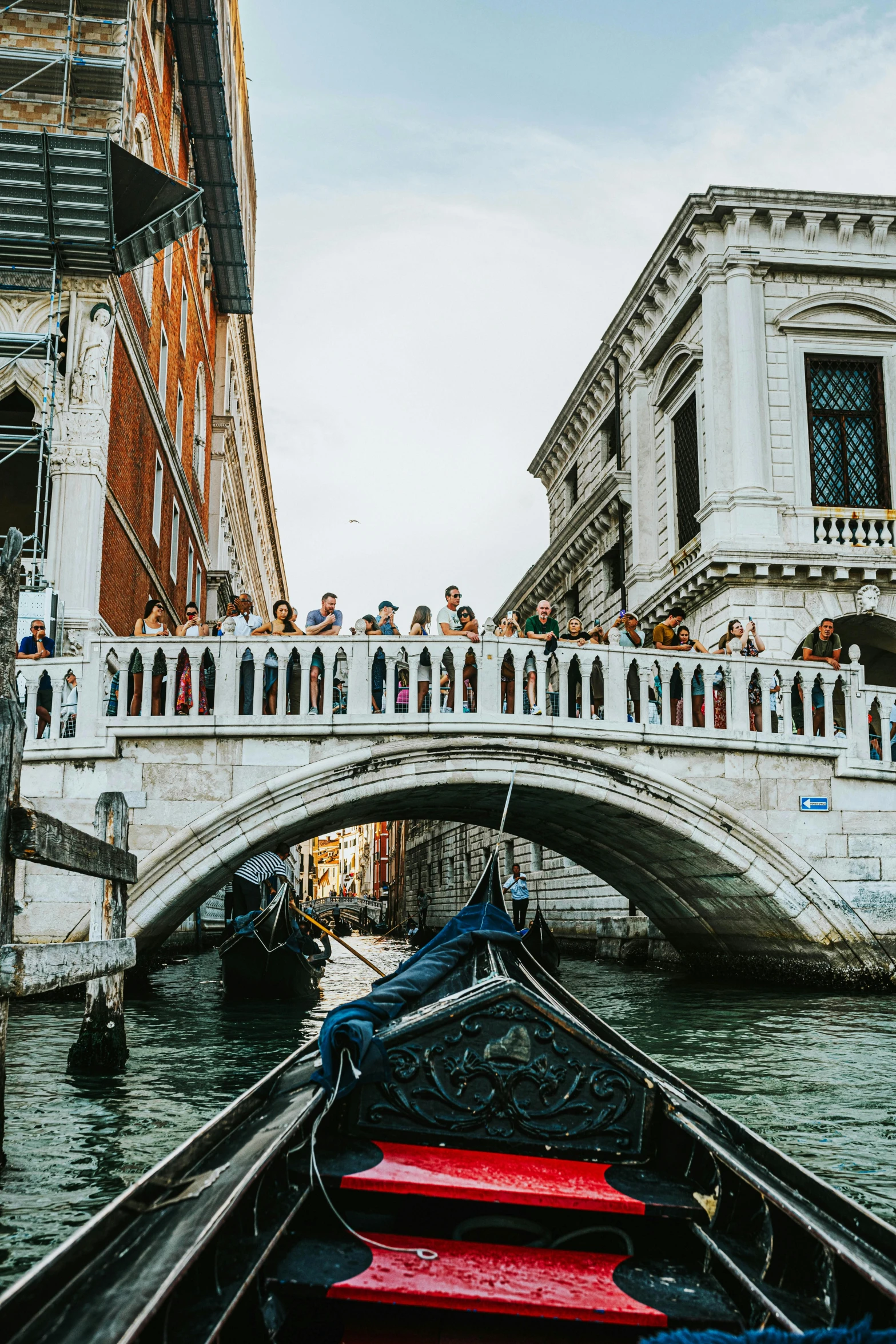 many people are standing outside near some buildings on a bridge