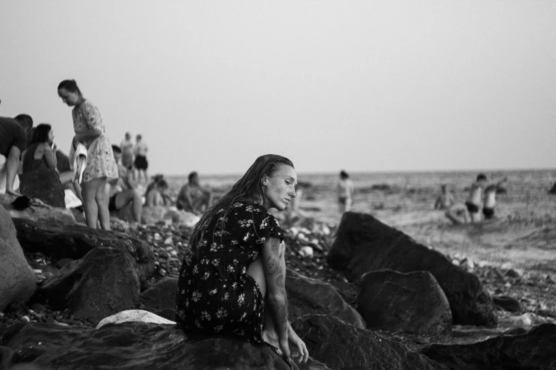 a woman sitting on some rocks near the beach