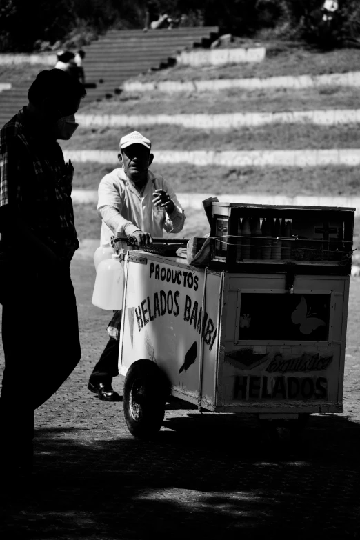 man in hat with street vendor selling items on cart