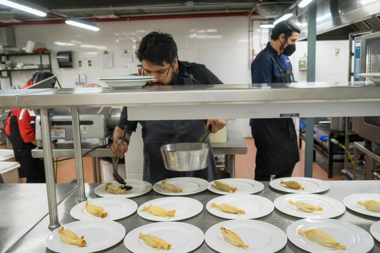 the men are working in the kitchen with plates of food