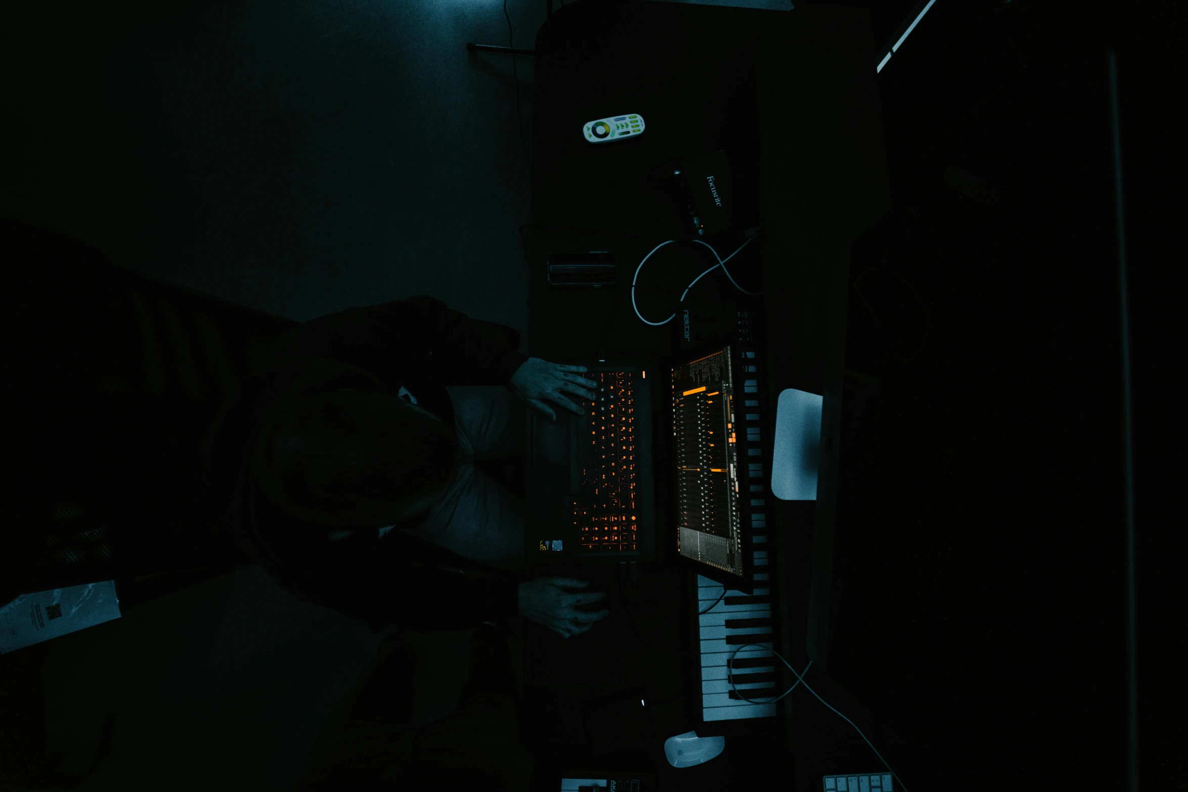 a man playing keyboard alone at night in a dark room