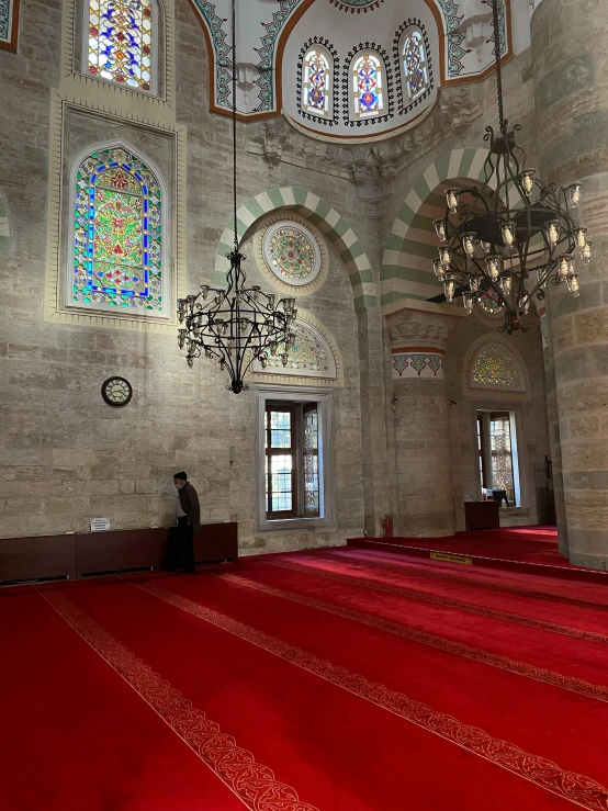 a grand hall with a bright red carpet and windows