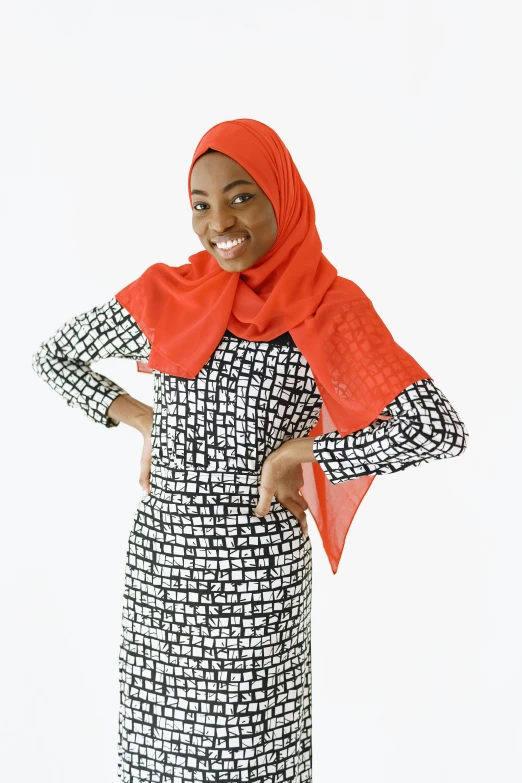 a woman poses in a patterned dress with orange scarf