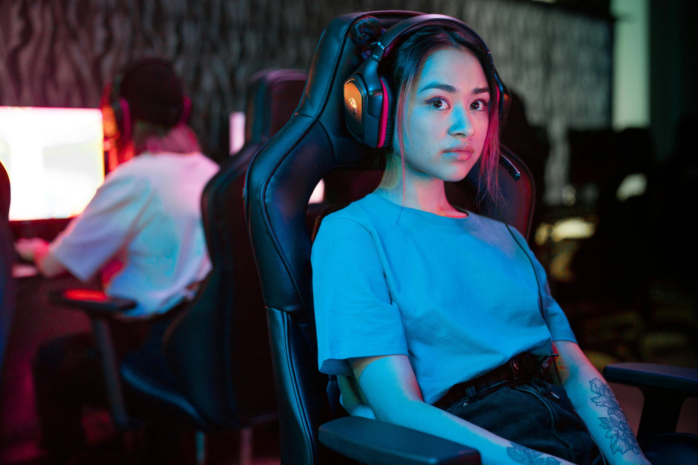 woman sitting in computer chair with headphones on and other people watching