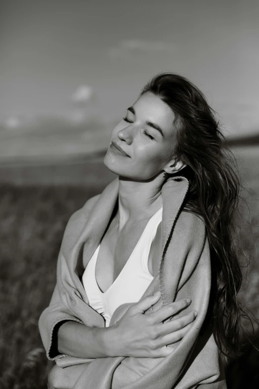 a woman wearing a jacket, stands in a field