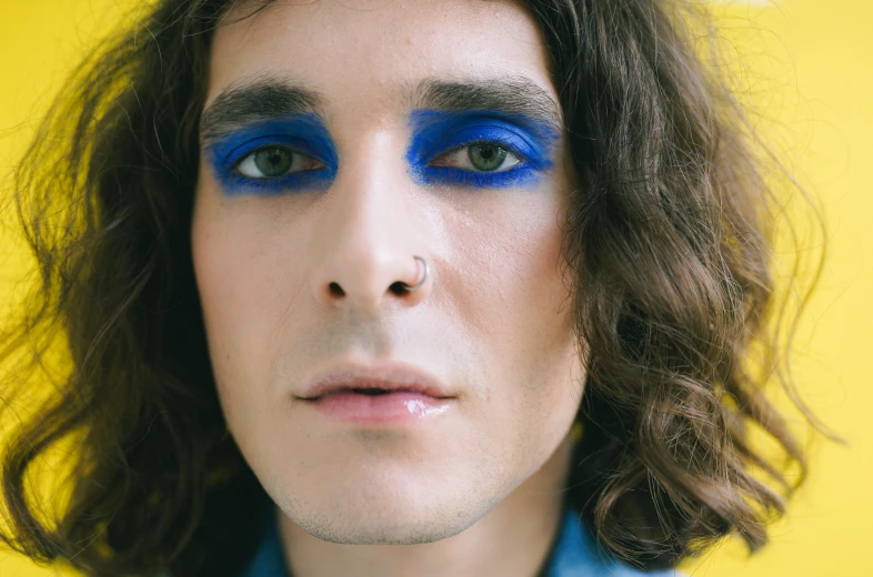 a man with long hair and blue eyes with blue makeup