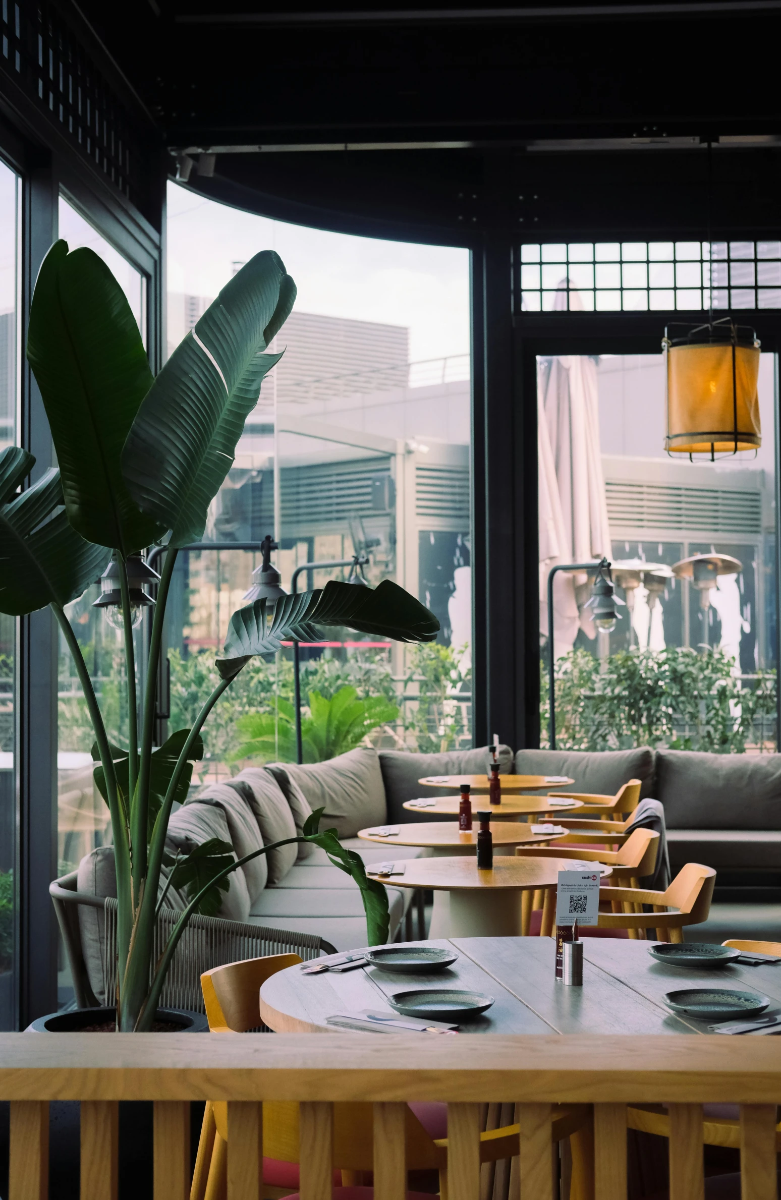 a room with wood tables and couches covered in green plants