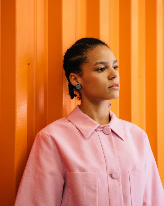 young black woman in front of orange wall wearing earrings