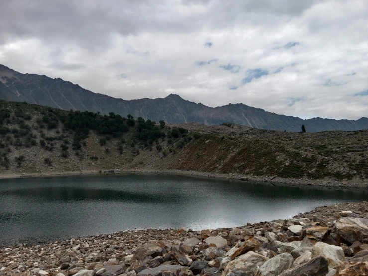a mountain range near a small lake with rocks