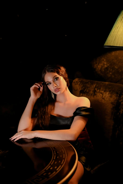 a woman in black sitting on the chair in front of a table