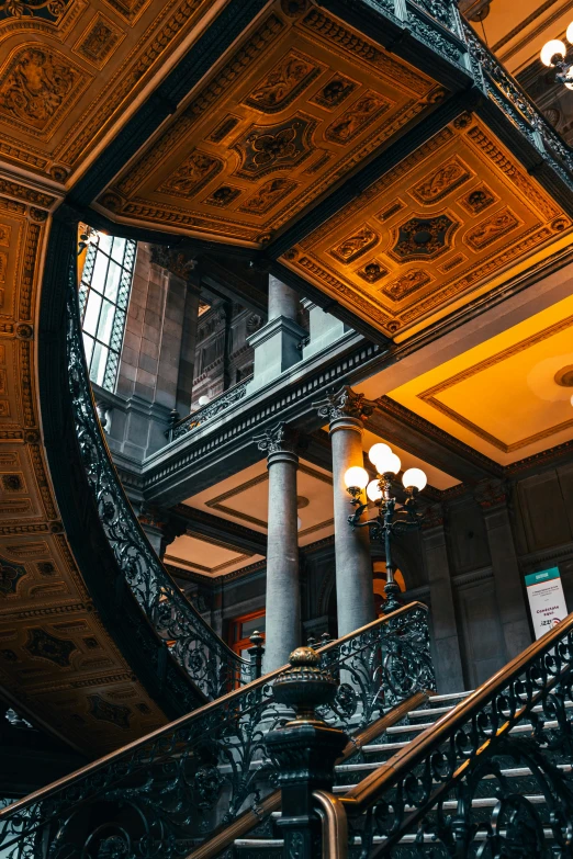 looking up at ornate stairs, with fancy ceiling and lights on them