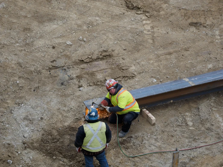 two people in safety vests work together with machinery