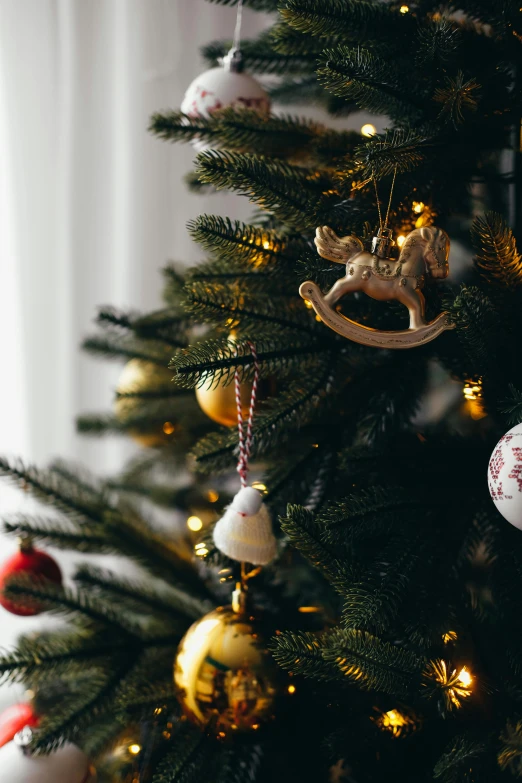 christmas decorations hang from the top of a green tree