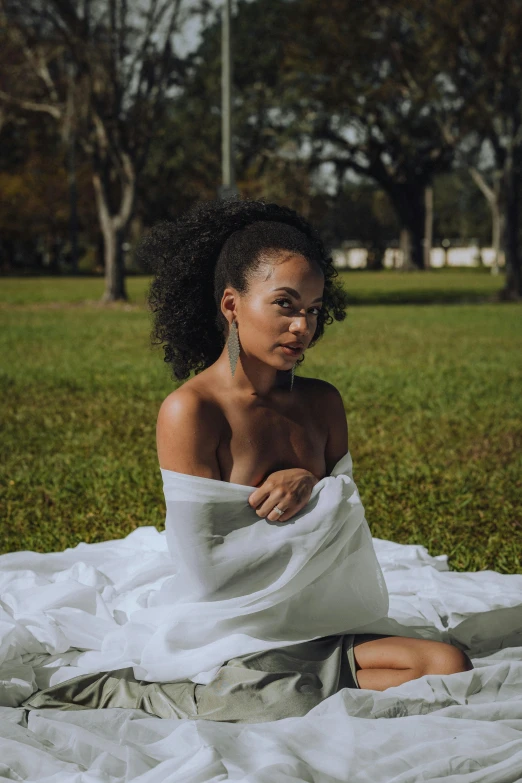 a woman sits on a white towel in the park