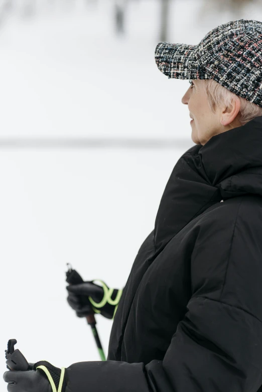 a woman with a hat and jacket holding skis