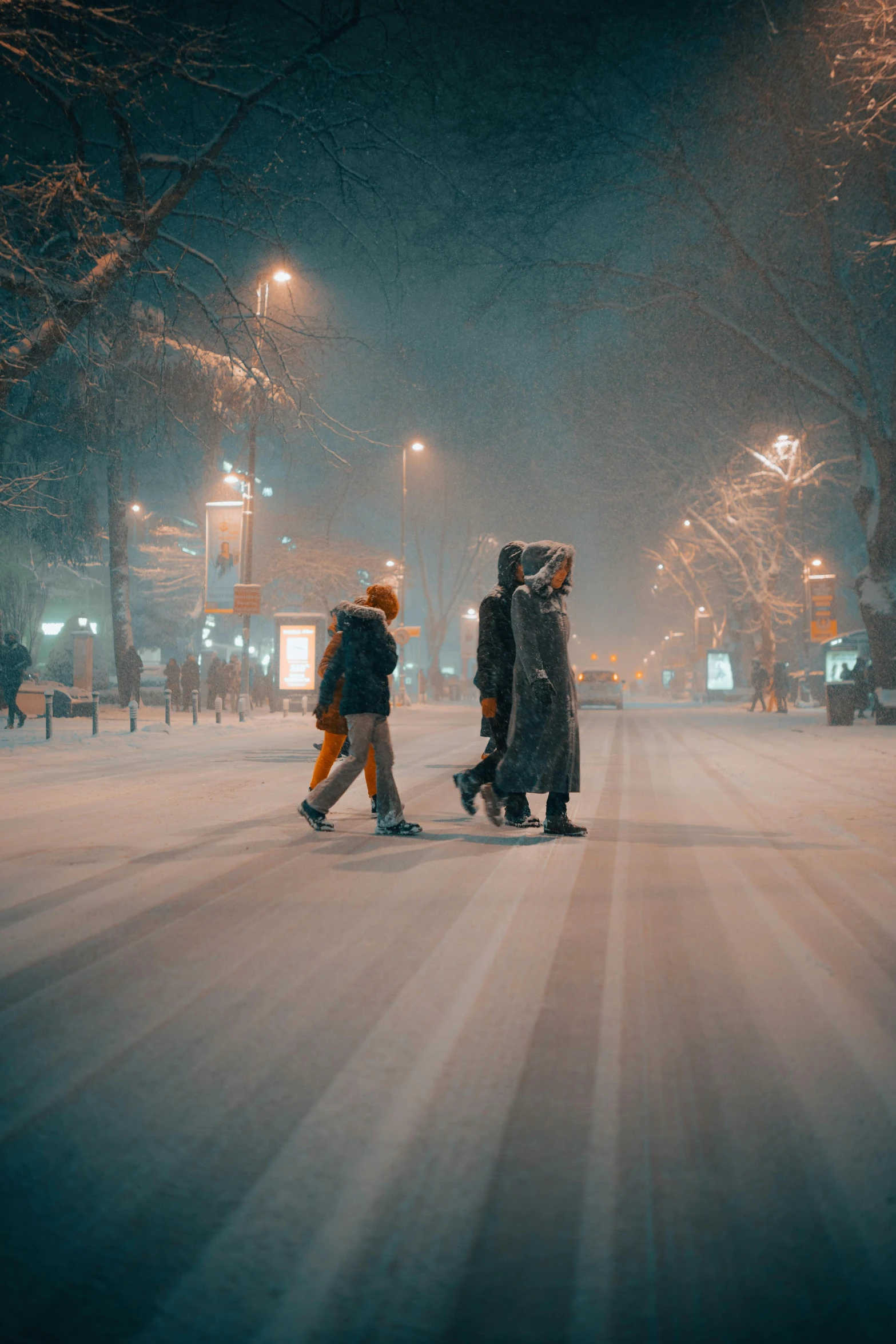 two people walking down a snow covered street at night