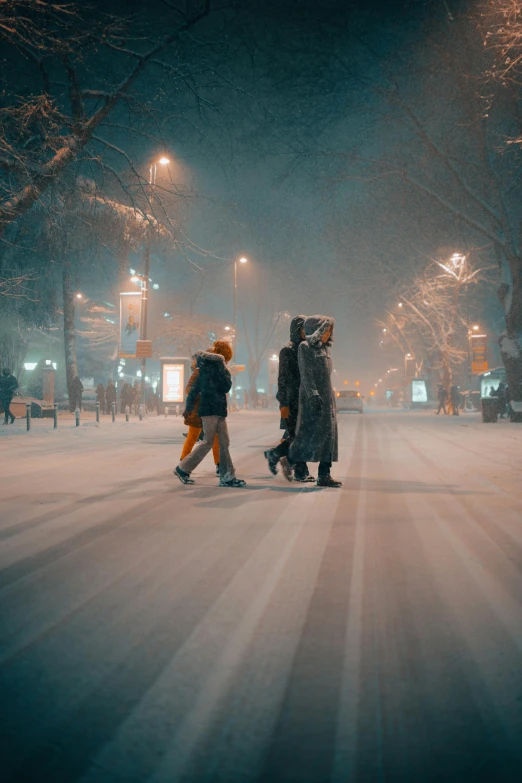 two people walking down a snow covered street at night