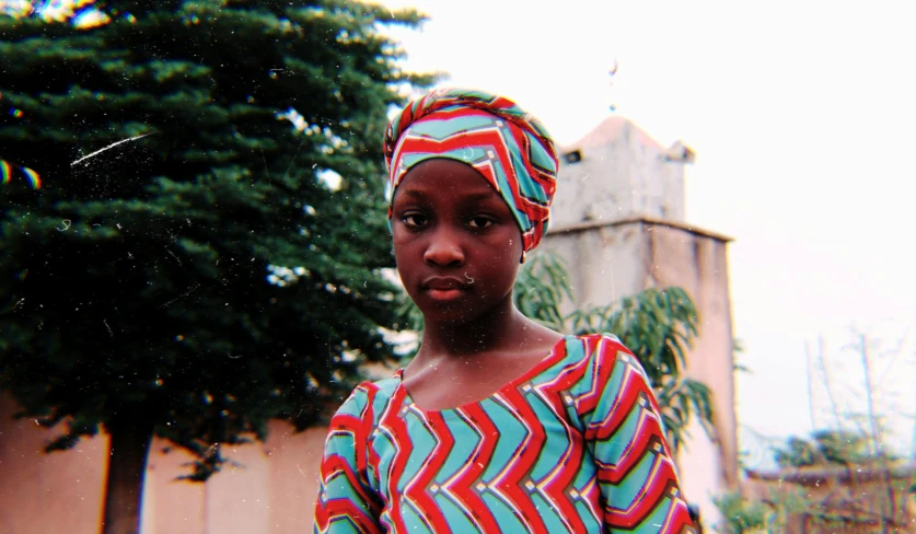 a girl wearing a turban standing in front of a building