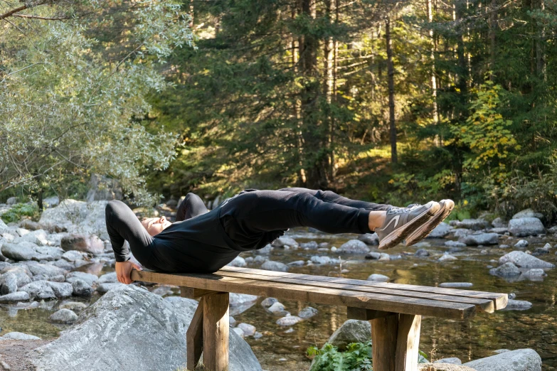 a man lays down on a wooden bench over water