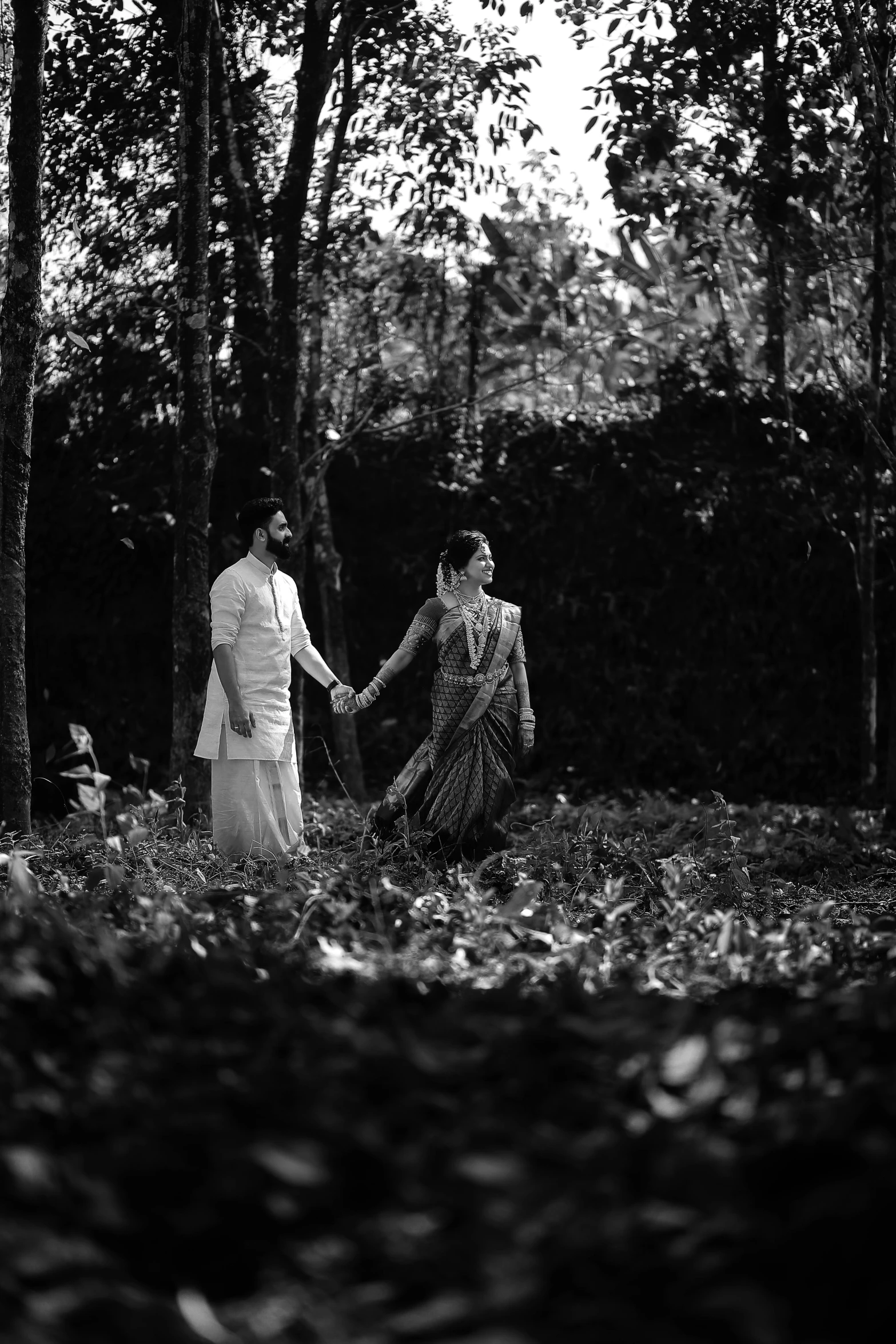 couple standing together in the forest in black and white