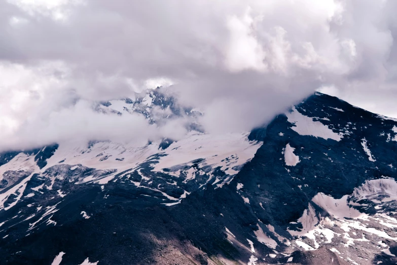 large snow - capped mountain rising into the cloudy sky