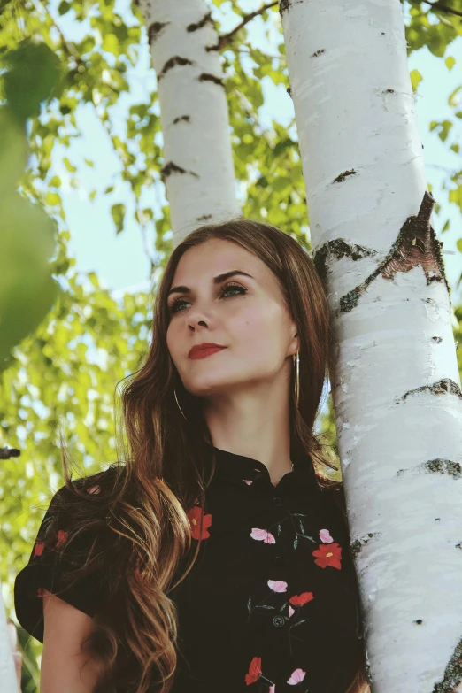 a beautiful woman standing between two white trees