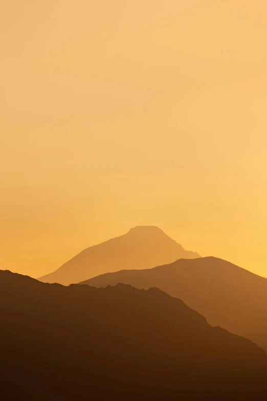 the silhouette of some hills at sunset, with one plane in the sky