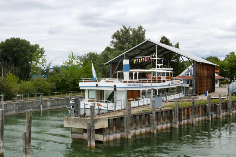 a house boat parked near the dock with people on it
