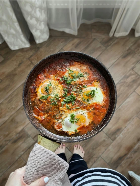 someone is holding a metal pan with a food dish on top