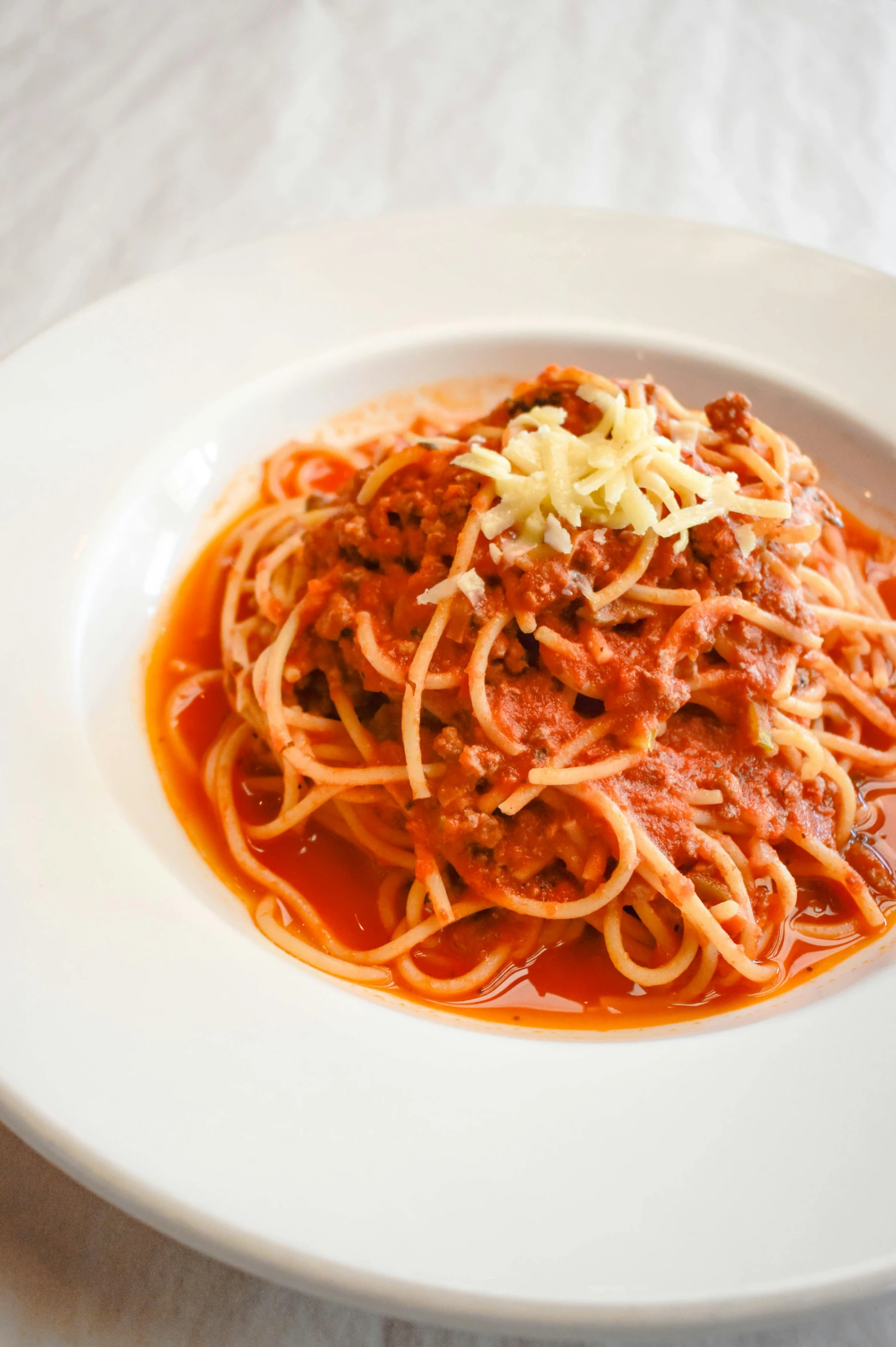 a plate full of spaghetti on a white table cloth