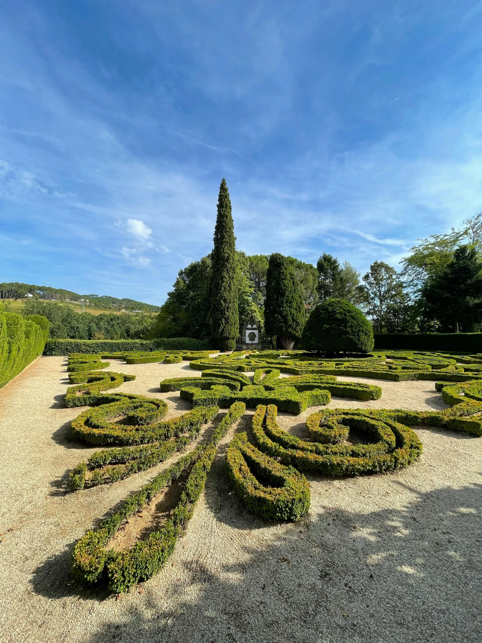 a small outdoor structure that has a circle shaped pattern made out of plants and bushes