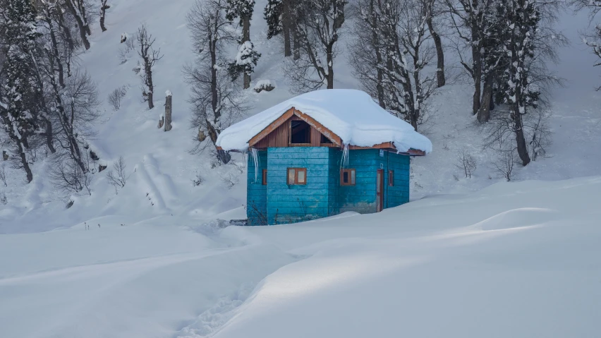 a hut with snow on the roof is in the middle of a field