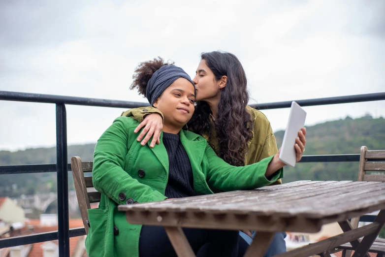 two women sitting at a table with an open book