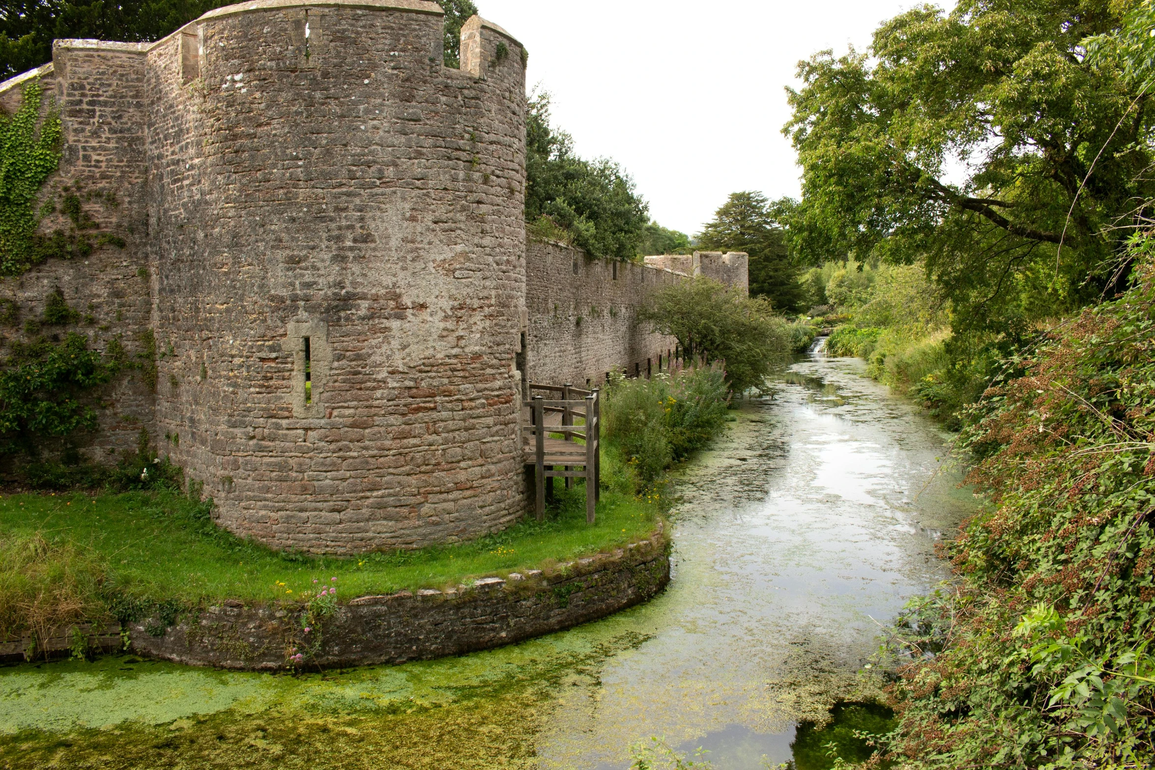 a river with a large brick tower next to some trees