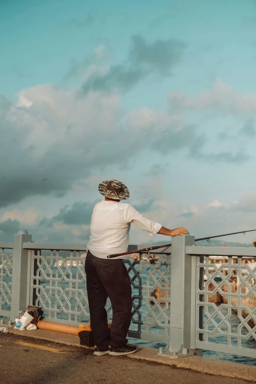 a man wearing a white shirt and black pants stands on a pier with his arms extended