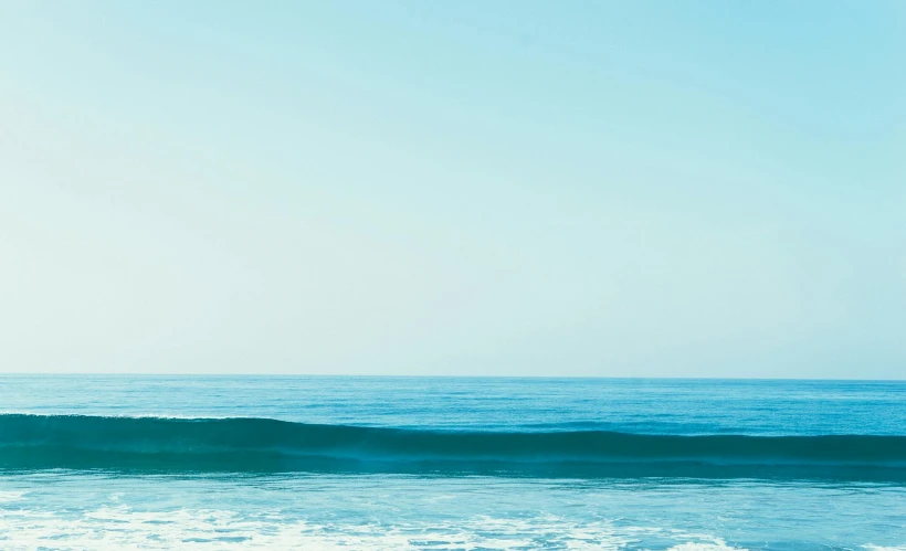 a man walking into the ocean on top of a surfboard