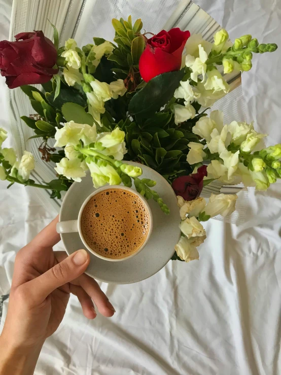 a coffee cup in front of a bouquet of flowers