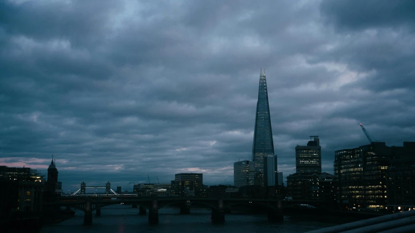 a tall tower sitting next to a large river under a cloudy sky